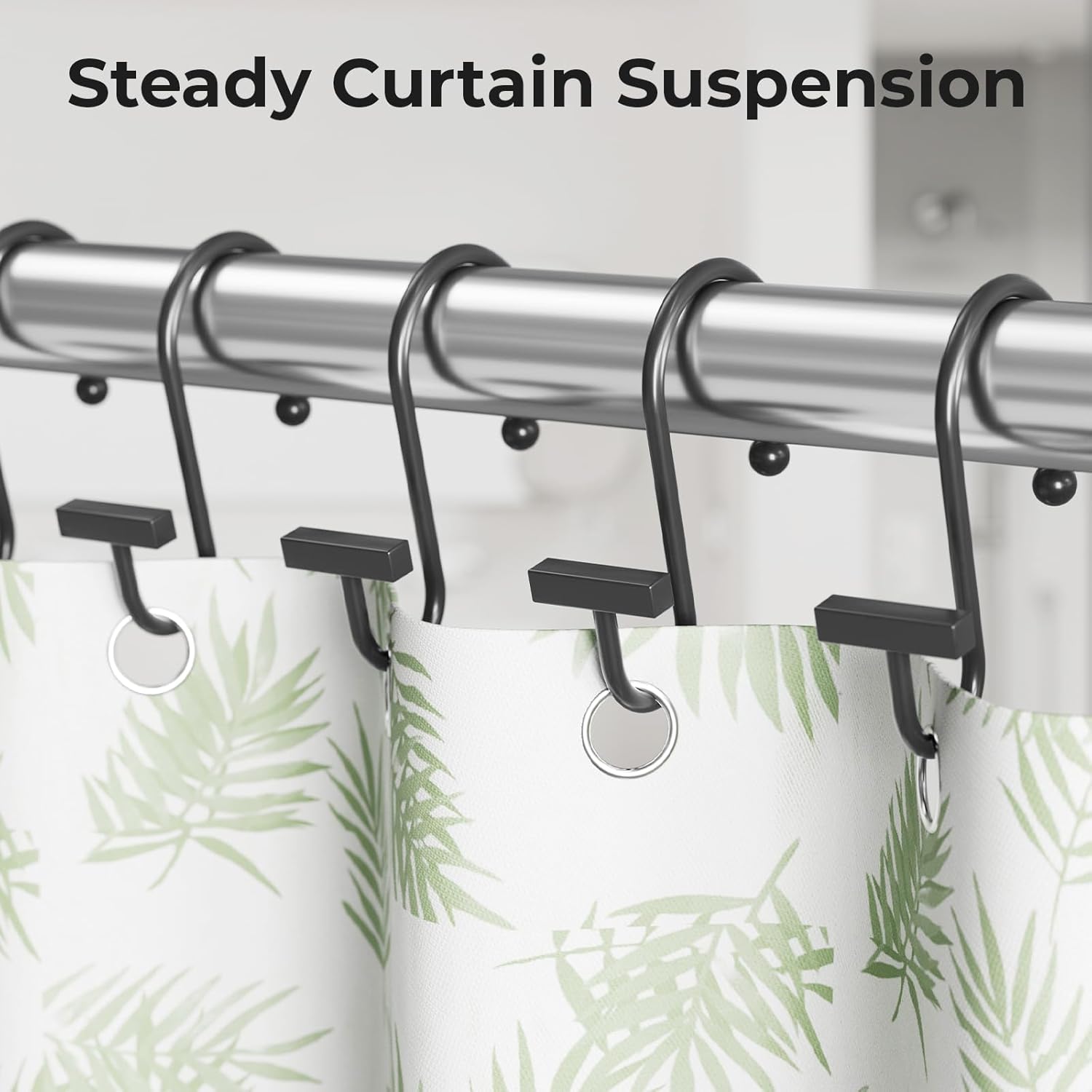 Curtain rod with black hooks holding a green leaf-patterned curtain.